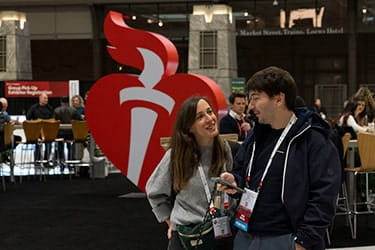 Man and women in front of Heart and Torch at Scientific Sessions 2023