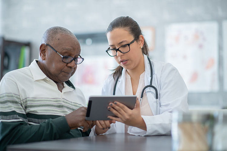 doctor sitting next to patient viewing tablet